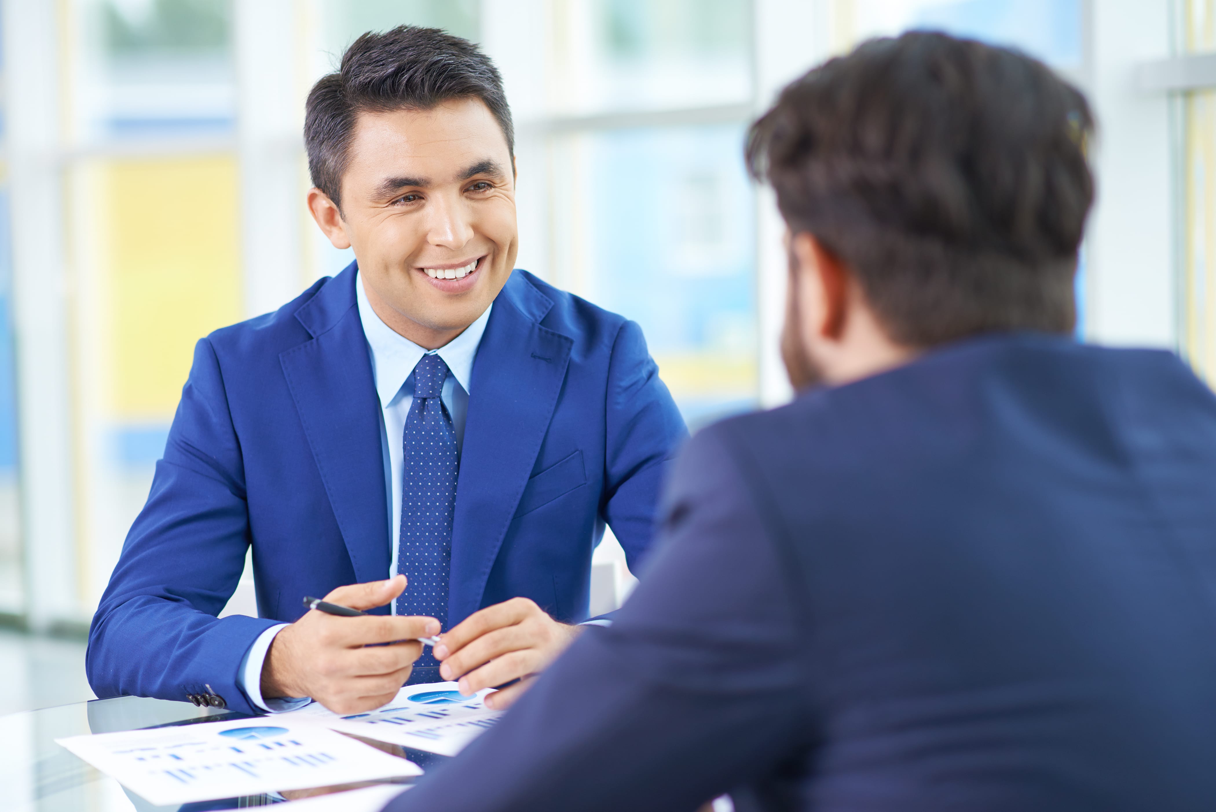 Image of handsome businessman in suit communicating with his colleague at meeting